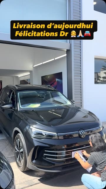 Livraison d'un Tiguan noir devant le showroom